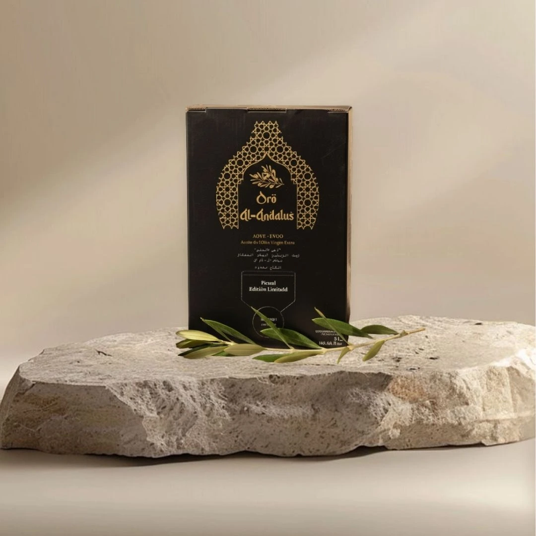 Oro Al Andalus Bib Queen 5L bag-in-box Extra Virgin Olive Oil in a black and gold Andalusian arch design box, on a travertine stone with a fresh olive branch